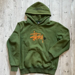 RARE! Stüssy Copyright hoodie  - Säljer en väldigt sällsynt grön stüssy copyright hoodie, Med fet orange broderad logga på bröstet och svart tryck i luvan. Klassisk känguruficka och ribbade muddar. Perfekt streetwear-vibe.