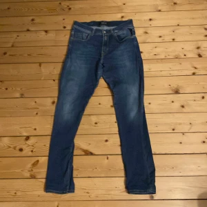 Blå slim fit jeans från Replay - Säljer ett par blå Replay storlek 31 32 med klassisk femficksdesign och snygga slitningar. Jeansen har normal midja och raka ben med en något smalare passform. Tillverkade i mjukt jeansmaterial med stretch för extra komfort. Perfekt inför hösten🔥