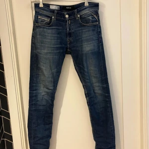 Replay Grover raka jeans blå - Snygga blå jeans från Replay, modell Grover med rak passform. Klassisk femficksdesign. Jeansen är tillverkade i denim och har en läderpatch bak i midjan. Perfekta för en avslappnad och stilren look. Den enda skavanken är att lappen där bak sitter lite löst 