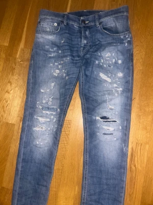 Dondup slim fit jeans - Säljer ett par blå jeans från Dondup med snygga slitningar och trasiga detaljer framtill. Modellen är skinny fit med klassisk femficksdesign och knappgylf. Jeansen har en fräsch tvätt och passar perfekt till en streetwear-look. Materialet är jeans och färgen är blå. Säljer pga resell. Det är bara fråga för mer bilder och pris kan dessutom diskuteras. 