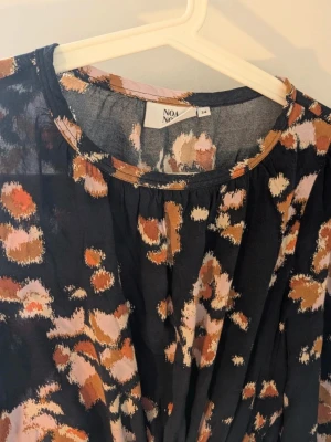 Mönstrad långklänning från Noa Noa - Supersnygg långklänning från Noa Noa med coolt mönster i svart, beige, rosa och brunt. Klänningen har långa ärmar, knytband i midjan och avslappnad passform. Perfekt för dig som gillar unika prints och vill sticka ut lite extra.