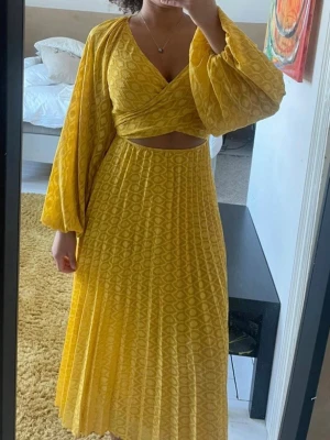 Gul långklänning - Superfin gul långklänning med omlott-topp, v-ringning och ballongärmar.💛 Klänningen har knyt i ryggen, plisserad kjol och ett fint mönster💛
