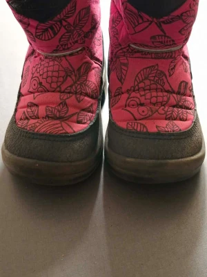 Kuoma vinterskor (barn) - Säljer ett par rosa vinterstövlar med svart ugglemönster och blad. Stövlarna har en robust svart sula och tåparti i syntetmaterial som tål slask och snö. Insidan är fodrad för extra värme och ovandelen är quiltad för en cool look.