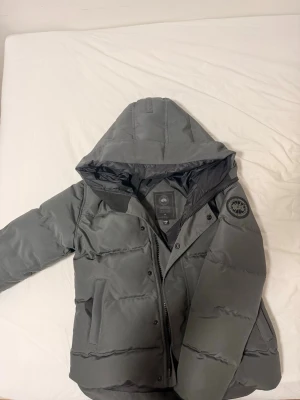 Grå pufferjacka från Canada Goose - Säljer en Grå black badge Macmillan jacka från Canada Goose. Nyskick på jackan, köpte jackan den här vintern, har inte kommit till mycket användning och det är anledningen jag säljer den. Jackan är i storlek S men kan även passa XS. Hämtas i Stockholm, kan även fraktas. Kom DM för övriga frågor!