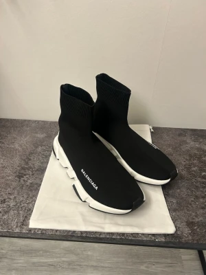 Speed sneakers svart/vit - Säljer ett par Speed sneakers i svart med vit chunky sula. Skorna har en strumpliknande design i stickad syntet och -logga på sidan och hälen. Platt sula och rund tå ger en clean och modern vibe. Perfekt för dig som gillar statement sneakers.