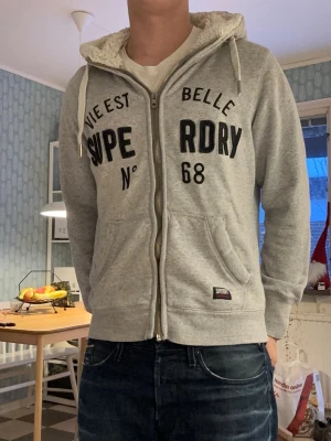 Superdry vintage fur zip up hoodie - En sjukt snygg, sällsynt och vintage superdry zip up hoodie med fodrad luva🤩 Väldigt sällsynt med bra passform och välfungerande dragkedja(defekt längst ned, påverkar inte funktionen, syns på sista bilden😁)! Passar storlek S, men det står xl på lappen! Är 176cm lång på bilden och passar folk som är mellan 170 och 176cm långa😁 Rintigt bra skick och inga slitningar! Tveka inte på att ställa frågor!