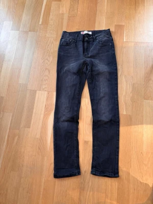 Levi's 512 mörkgrå jeans - Snygga mörkgrå Levi's 512 jeans med klassisk femficksdesign och raka ben. Jeansen har en slim taper passform och är tillverkade i mjukt jeansmaterial med lite stretch för extra komfort. Perfekta för dig som gillar en stilren och modern look. Insydd resår i midjan för mer flexibilitet i mått.