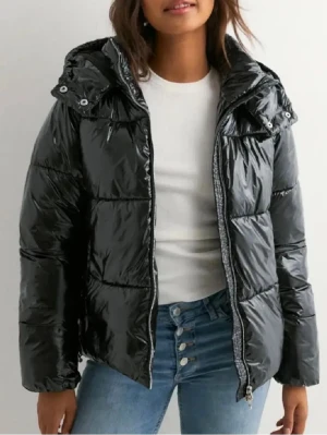 Svart pufferjacka  - Snygg svart pufferjacka med glansig yta och huva. Jackan har en rak passform, dragkedja framtill och quiltade sektioner som ger en cool look. Perfekt för dig som vill ha en varm och trendig jacka till kyliga dagar. Pris kan diskuteras!