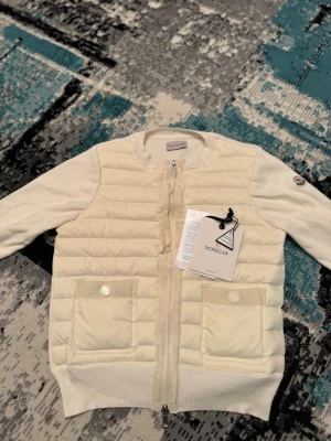 Moncler cardigan  - Säljer en fin stilig klassisk moncler cardigan i den vita färgen som får jackan att sticka ut lite mer perfekt för en enkel stilren look skriv om det är något du undrar 😊