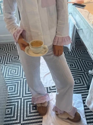 Meet Me There pyjamasbyxor  - Helt nya superfina vita pyjamasbyxor med volangdetaljer i rosa- och vitrandigt tyg längst ner. Det är pyjamasbyxorna från Filippas kollektion. De är helt nya aldrig använda! Nypris 450kr! Storlek: XXS/XS