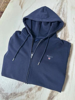 Gant zip hoodie - Säljer min gamla zip hoodie som är från gant. Tröjan har inga hål eller defekter förutom att det finns väldigt lite vit färg som knappt syns längst nere vid tröjan (se bild) bortsätt från det är tröjan i storlek M. Har du flera frågor så är det bara att skriva till mig!😊💕