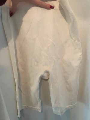 Vita ribbade leggings - Säljer ett par vita ribbade leggings i mjukt material. De har en enkel och clean look med smal passform och stretchig midja. Perfekta att styla med oversized tröja eller hoodie för en chill vibe.