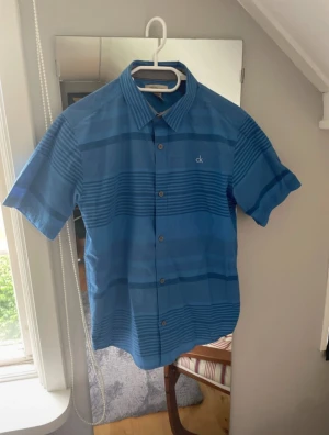 Skjorta Calvin Klein - Mycket fin blå skjorta från Calvin Klein. Storlek 14/16 år.