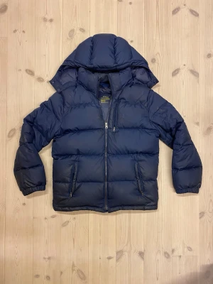 Mörkblå  Ralph Lauren jacka  - Säljer en fet Ralph Lauren jacka i storlek 160 cm, den är bra skick med tanke på puffigheten men lite små fläckar. Det går att tvätta bort om man vill de. Skriv för frågor eller likande. Kan även ta emot byten 