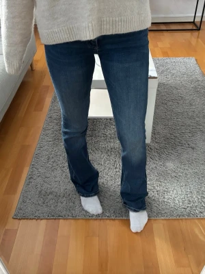 Blå bootcut jeans från Zara - Snygga blå bootcut jeans från Zara i storlek 34. Jeansen har klassisk femficksdesign, dragkedja och knapp framtill samt bälteshällor. Materialet är mjukt denim i bomull med lite stretch för skön passform. Perfekt till sneakers eller boots.