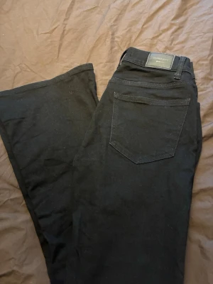 Svarta bootcut jeans från Ginatricot, strl 36 - Säljer ett par svarta utsvängda jeans storlek 36. Använda en gång. 
