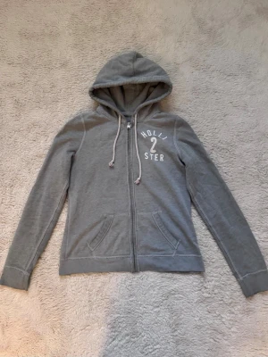 Grå zip up Hoodie Hollister  - Grå zip up Hoodie ifrån Hollister i storlek M, i använt skick! 