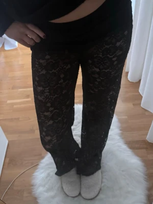 Svarta vida spetsbyxor - Säljer ett par svarta byxor i transparent spets med blommigt mönster. Från design by si. Ny skick förutom att det är två håll längst ner i de ena byxbenet men som man inte alls tänker på , hör av er för mer bilder💖säljer lite dyrare då xs är helt slutsålt
