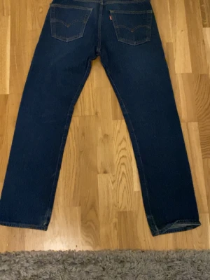Levi's 501 jeans mörkblå W29 L32 - Mörkblå klassiska Levi's 501 jeans med raka ben och fem fickor. Jeansen har knappgylf och tydliga kontrastsömmar. Modellen är straight och tillverkad i slitstarkt jeanstyg. Passar dig som gillar tidlös stil och vill ha ett par jeans med ikonisk look. Pris går tyvärr inte att diskuteras. Köptes från Levis hemsida.