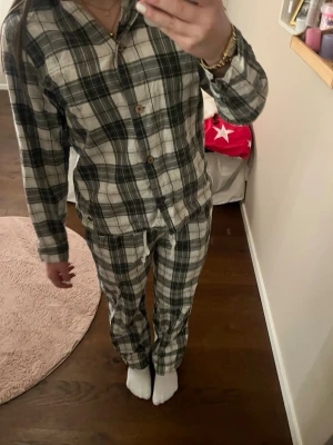 Rutig pyjamas från Pernilla Wahlgrens märke XS - Säljer en rutig pyjamas från Pernilla Wahlgrens märke i vitt och mörkgrönt. Skjortan har klassisk krage, knappar framtill och är gjord i mjuk bomull. Perfekt för dig som gillar avslappnad och trendig stil.