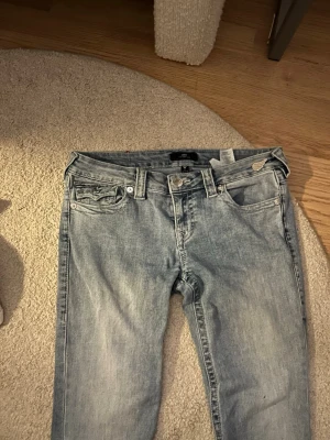 True Religion Joey Low Rise Flare Jeans - Säljer ett par ljusblå True Religion Joey jeans med låg midja i str 28. Saknas en knapp där bak men går lätt att sy fast en ny