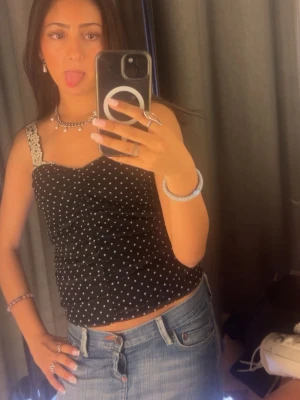 Svart prickig tubtopp - Säljer en svart tubtopp med vita prickar och lätt rynkad effekt. Toppen är axelbandslös och har en luftig känsla, perfekt för varma dagar. Materialet känns som tunn polyester. Helt ny aldrig använd men ingen prislapp på. Finns inte längre var ganska populär. 