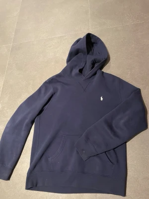 Mörkblå Ralph lauren hoodie  - Halloj!! Jag säljer denna riktigt fina och eftertraktade Ralph lauren hoodien. Hoodien är i en riktigt fin navy blå färg. Perfekt för dig som söker en riktigt clean look, den passar perfekt till ett par schyssta jeans. Ny pris är 1199, mitt pris är 499, priset är inte hugget i sten 🪨 