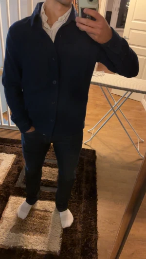 Mörkblå overshirt från D once de la sense - Snygg mörkblå overshirt med klassisk krage och raka linjer. Jackan har två stora bröstfickor, knappar hela vägen och långärmade ärmar. Materialet är mjukt och håller bra i kylan perfekt för lager-på-lager. Diskret broderad logga på ärmslutet.