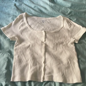 Brandy Melville - Vit ribbad topp med knappar - Säljer en vit ribbad topp med kort ärm och knappar framtill från BM, för att se passform har jag en annan annons med Likadan modell fast i svart! (Aldrig använd enbart provad) har fabriksdefekter/lite tråd som sticker ut vid den högra underarmen (lätt att klippa bort/fixa) One Size men skulle säga XS-S, Frågor ? Kom DM 