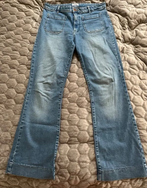 Ljusa jeans från Wrangler - Fina ljusblå jeans från Wrangler. Fina fickor framtill och en sydd kant längst ner på byxbenen. Använda fåtal gånger. Storlek 38/40. Eventuella veck som syns på bilden medföljer inte vid köp! 