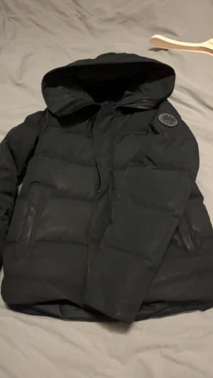 Svart pufferjacka från Canada Goose - Black label Macmillan parka Canada Goose. Size S. 5/10 skick. Några skrapor på armarna samt ett hål under armhålan som är lagat