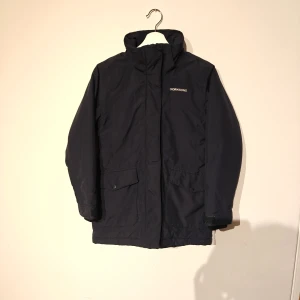 Didriksons vinterjacka - Parkas från Didriksons i mörkblått med huva och fuskpäls. Jackan är 100% vattentät och har mjukt teddyfoder på insidan. Praktiska fickor med lock och justerbara ärmslut med kardborre. Perfekt för kalla och blöta dagar.