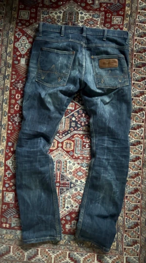 Wrangler jeans  - Säljer ett par wrangler jeans i klassisk blå tvätt med snygg tvätt och kontrastsömmar. Modellen har raka ben, fem fickor och läderpatch bak. Jeansen är tillverkade i robust denim och har en normal passform.