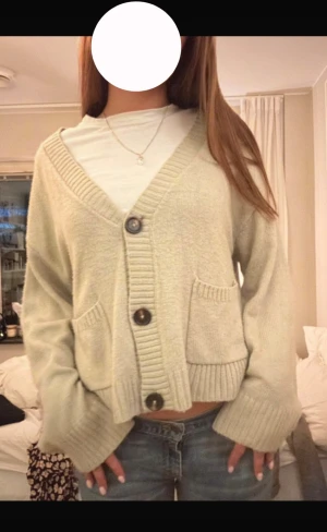 Beige/korall grön  stickad kofta med knappar - Supermysig beige stickad kofta med grova ribbade muddar och tre stora knappar framtill. Koftan har två praktiska fickor och en croppad passform som ger en chill vibe. Perfekt att slänga över en t-shirt för en avslappnad look.(lånade bilder) säljer då den var för stor för mig, den är lite nopprig