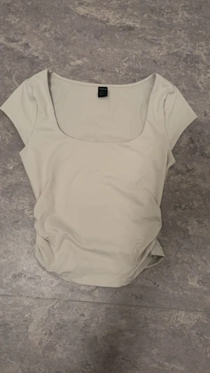 Beige topp med fyrkantig ringning Shein - Säljer en stilren beige topp från Shein med korta ärmar och snygg fyrkantig ringning. Toppen är i mjukt och stretchigt material, perfekt att matcha med jeans eller kjol. Enkel och clean design som funkar till många looks.