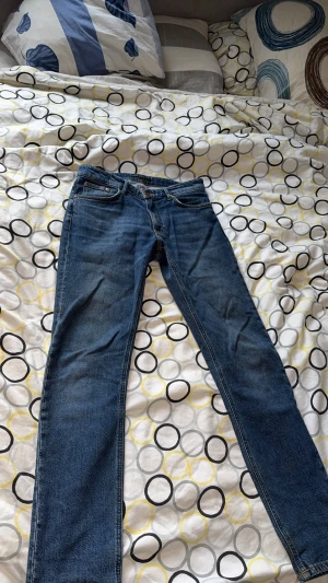 Nästan nya Nudie Jeans Mellow Mae Blue Mud - Säljer ett par Nudie Jeans Mellow Mae i färgen Blue Mud. Klassiska blå jeans med snygga kontrastsömmar och detaljerade fickor. Materialet är 99% bomull och 1% elastan för lite stretch. Passformen är rak och de har normal midja.