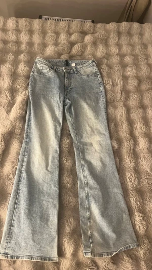 Ljusblå bootcut jeans - Säljer ett par ljusblå jeans med bootcut-modell från H&M. Jeansen har klassisk femficksdesign och är tillverkade i denim. Perfekta för dig som gillar en retro och trendig look. Dom är dock nertrampade så de är lite slitna ner till.