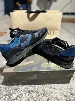 Valentino rockrunners - Blå valentino rockrunners i nästan helt nytt skick. Storlek 44. De är svarta med blå camouflage. Skorna är självklart äkta men box ingår inte men finns kvar så kan följa med vid förhandling