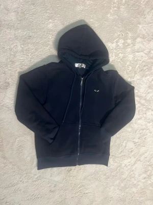 CDG Zip - Snygg Cdg zipp i marinblå med svart hjärta på ryggen som är i toppskick, den är använd ett fåtal gånger men är helt felfri. Den har även fleece på insidan vilket gör den varm och perfekt inför vintern:) (passar 165-177