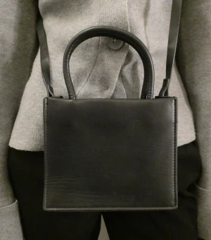 Väska  - Liten enkel svart väska med två handtag och justerbart längre axelband