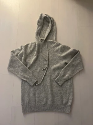 Grå merinoull hoodie med huva -  Grå hoodie i merinoull material. Storlek S. Mycket fint skick men lite av början av luvan har lossnat (se bilden)