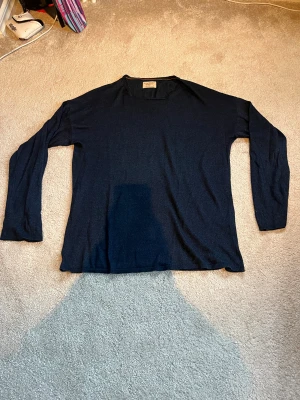 Mörkblå långärmad tröja Nudie Jeans  - Snygg mörkblå långärmad tröja från Nudie Jeans Co i storlek M. Tillverkad av 100% ekologisk bomull, med enkel och clean design utan mönster eller detaljer. Perfekt för dig som gillar stilrena och bekväma plagg.