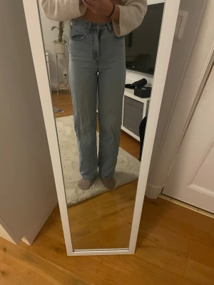 Ljusblå raka jeans med hög midja - Säljer ett par ljusblå jeans med hög midja och raka ben. Priset kan diskuteras. Jeansen har klassisk femficksdesign och stängs med dragkedja och knapp. Perfekta för en avslappnad och trendig look. Materialet är klassisk denim i bomull.