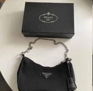 Ny väska  - Aldrig använd, i nyskick. Kan bäras både på axeln eller crossbody beroende på om man vill använda kedjan eller remmen. Obs lådan ingår inte! 