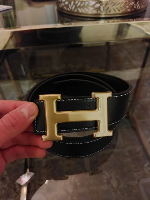 H Bälte Guld Svart - ● Ny och aldrig använt. Litet verktyg för att göra hål med är inkluderad 👍  ● Storlek: 110cm.   ● Fraktar inom 24h, så att du får paketet så fort som möjligt! 📦 Vid frågor eller intresse, dm. 😁
