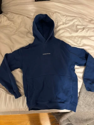 Hoodie - Snygg blå hoodie från Yoke med trycket 'ALTERED FUTURE' på bröstet. Klassisk design med stor huva och magficka. Mjuk bomullskänsla och ribbade muddar vid ärmar och nederkant. 