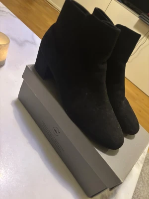 Svarta mocka boots från DIN SKO - Snygga svarta boots från Din Sko i mjuk mocka med rund tå och stabil låg klack. Skorna har dragkedja på sidan för enkel på- och avtagning. Perfekt till höst och vinter för en stilren look.