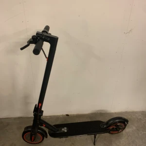 Elsparkcykel V2 - Svart elsparkcykel med röda detaljer, robust konstruktion och hopfällbar design. Synligt slitage på hjul och fotplatta, men i fungerande skick. Perfekt för smidig pendling i stadsmiljö. Laddare och tillbehör ingår ej.