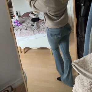 Lågmidjade True Religion bootcut jeans i ljusblå denim - Säljer ett par lågmidjade bootcut jeans i ljusblå tvätt med klassiska fem fickor och snygga detaljer på bakfickorna. Jeansen har dragkedja och knapp framtill, och är tillverkade i mjukt denim-material som sitter skönt och ger en cool siluett. 💞 Passar både S och M då de är stretchiga 💞