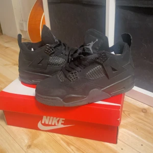 Nike Air Jordan 4 Retro Svart - Skorna är lite små i storlek. Nike Air Jordan 4 Retro i helsvart färg med klassisk Jumpman-logga på hälen. Skorna har meshpaneler, snörning och robust platt sula. Materialet är en mix av skinn och syntet, med detaljer i plast och mesh för extra streetkänsla. Perfekt för dig som gillar ikoniska sneakers.